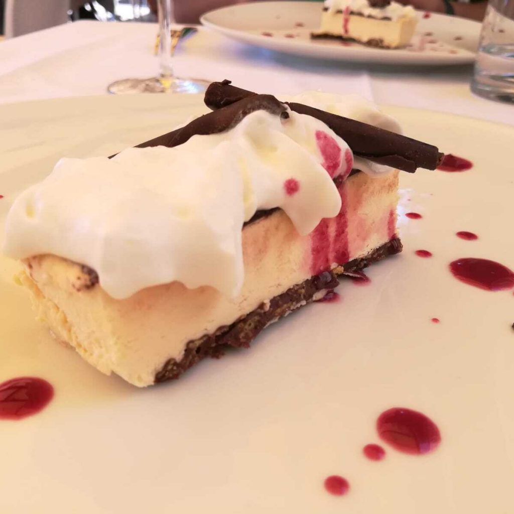 Mattoncino vaniglia e cioccolato bianco su terra di cacao e gocce di lampone.